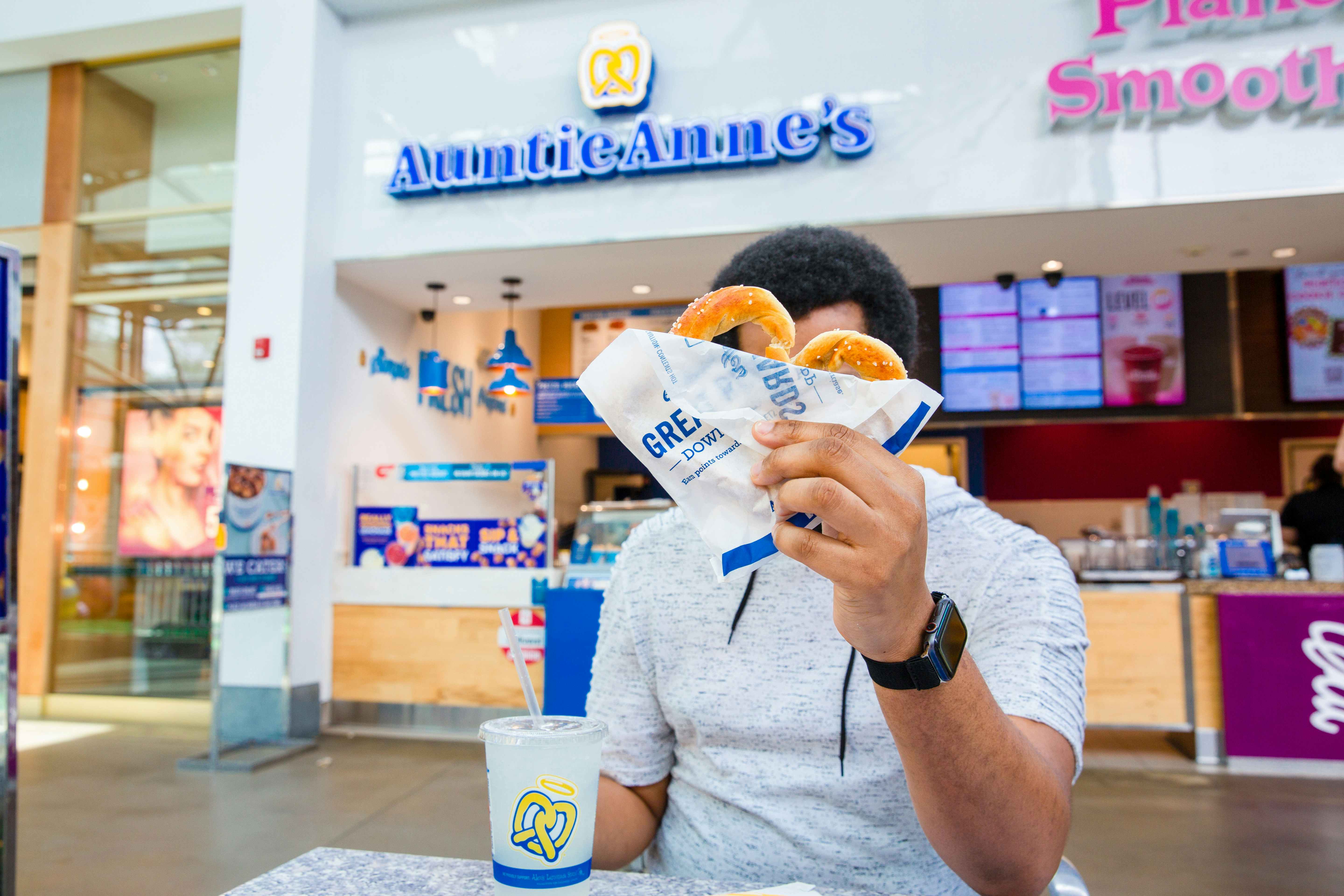 Person holding an auntie anne's pretzel in front of the store