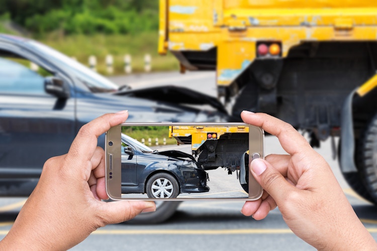 Close up hand of woman holding smartphone and take photo of car accident