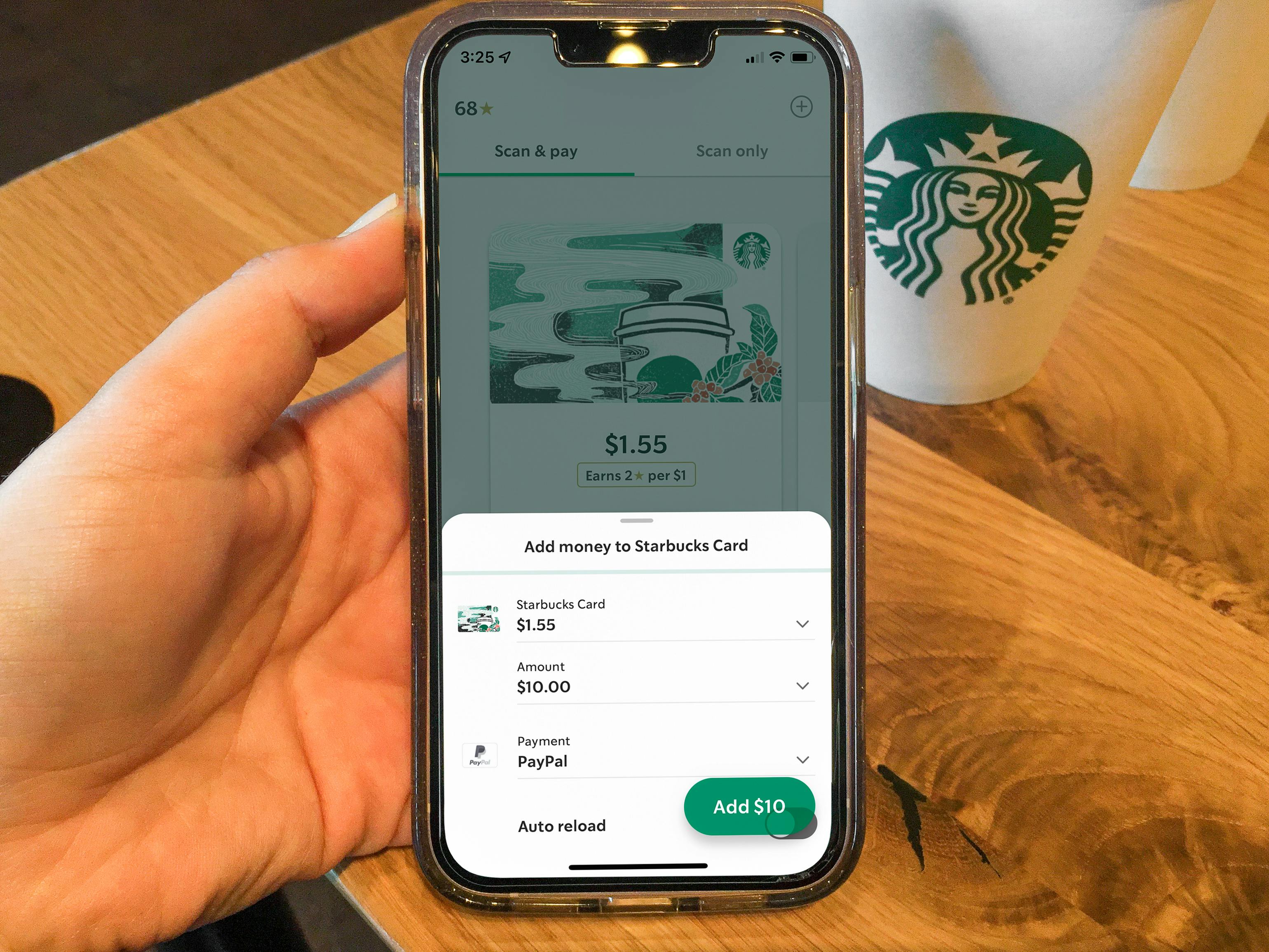 A person holding their phone displaying the Starbucks app balance reload screen.