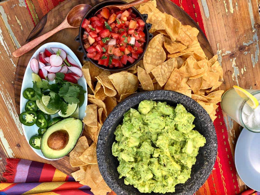 A platter with guacamole , salsa, and chips.