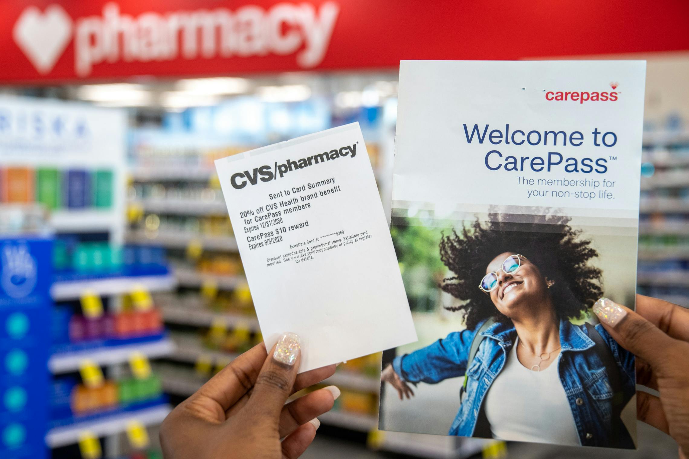 A person holding an CarePass rewards pamphlet inside CVS.
