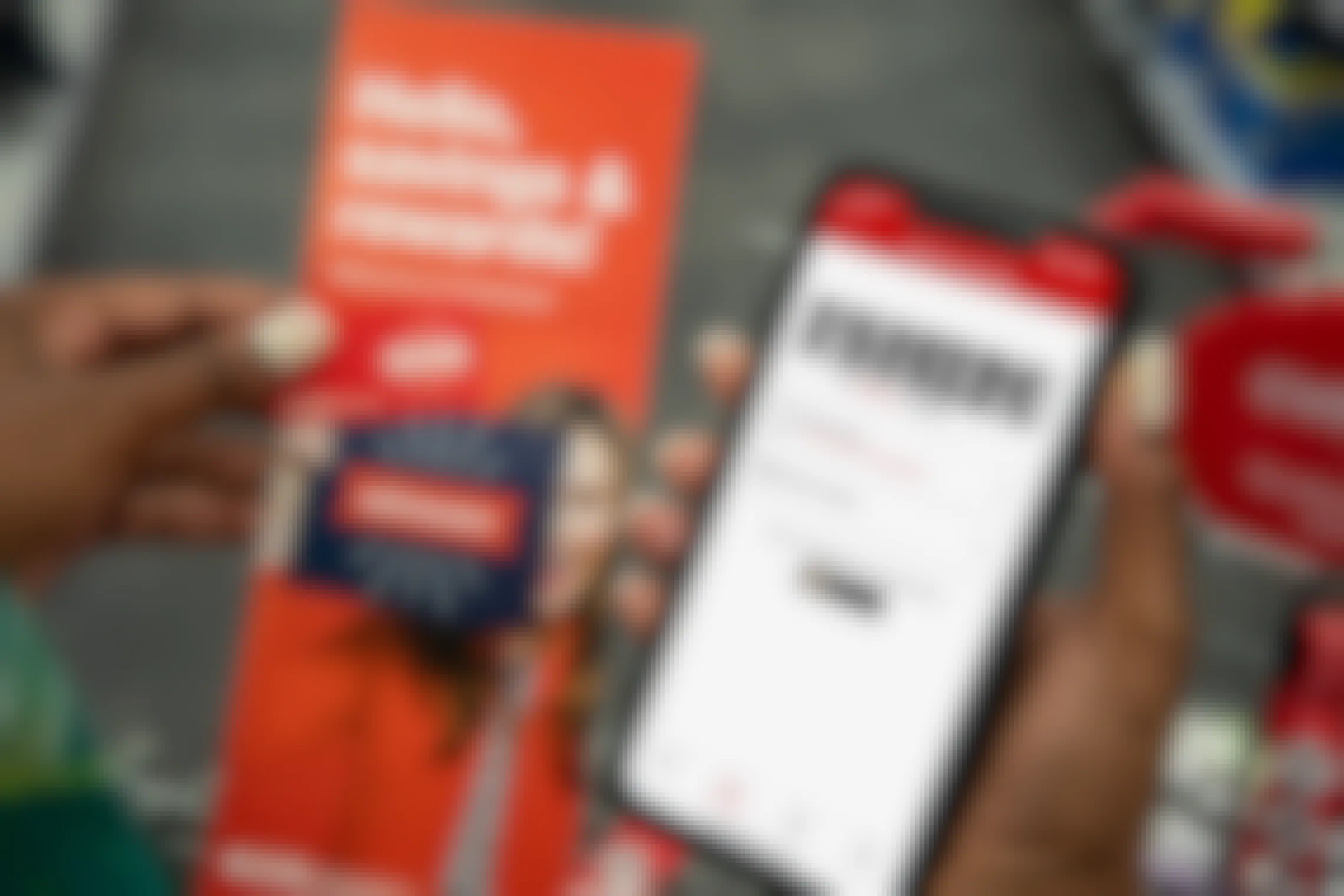 A woman holding an iphone with the CVS app, a rewards key chain card, and an extracare rewards pamphlet.
