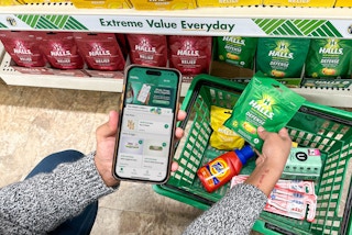 a person holding an iphone with a coupon app in the dollar tree store