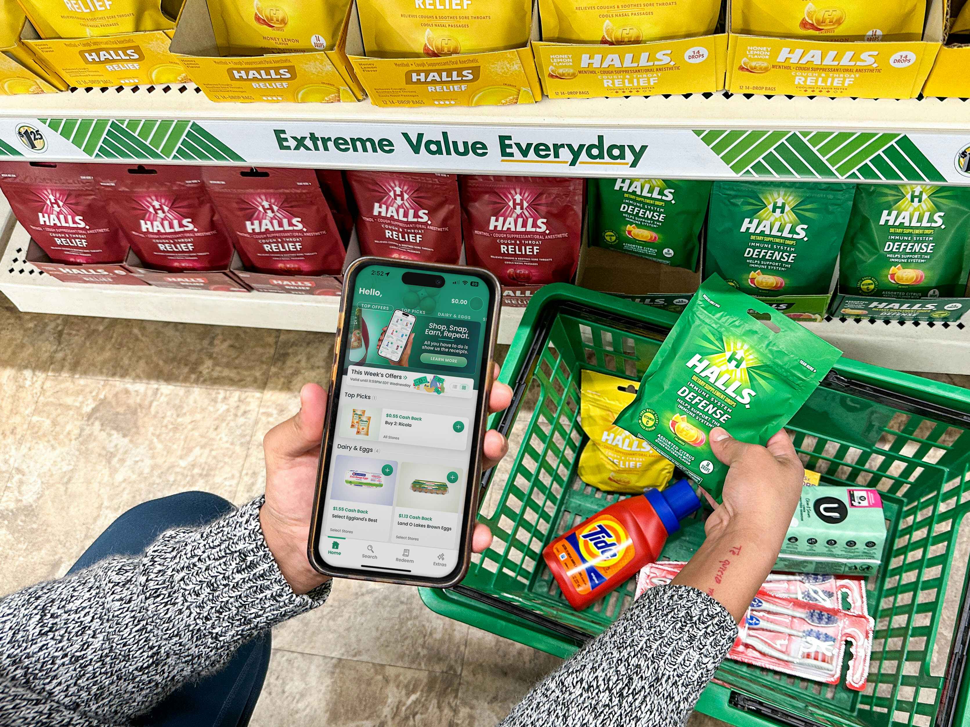 a person holding an iphone with a coupon app in the dollar tree store