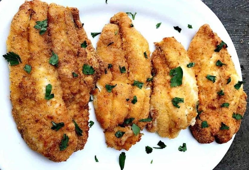 Breaded catfish on a plate sprinkled with parsley
