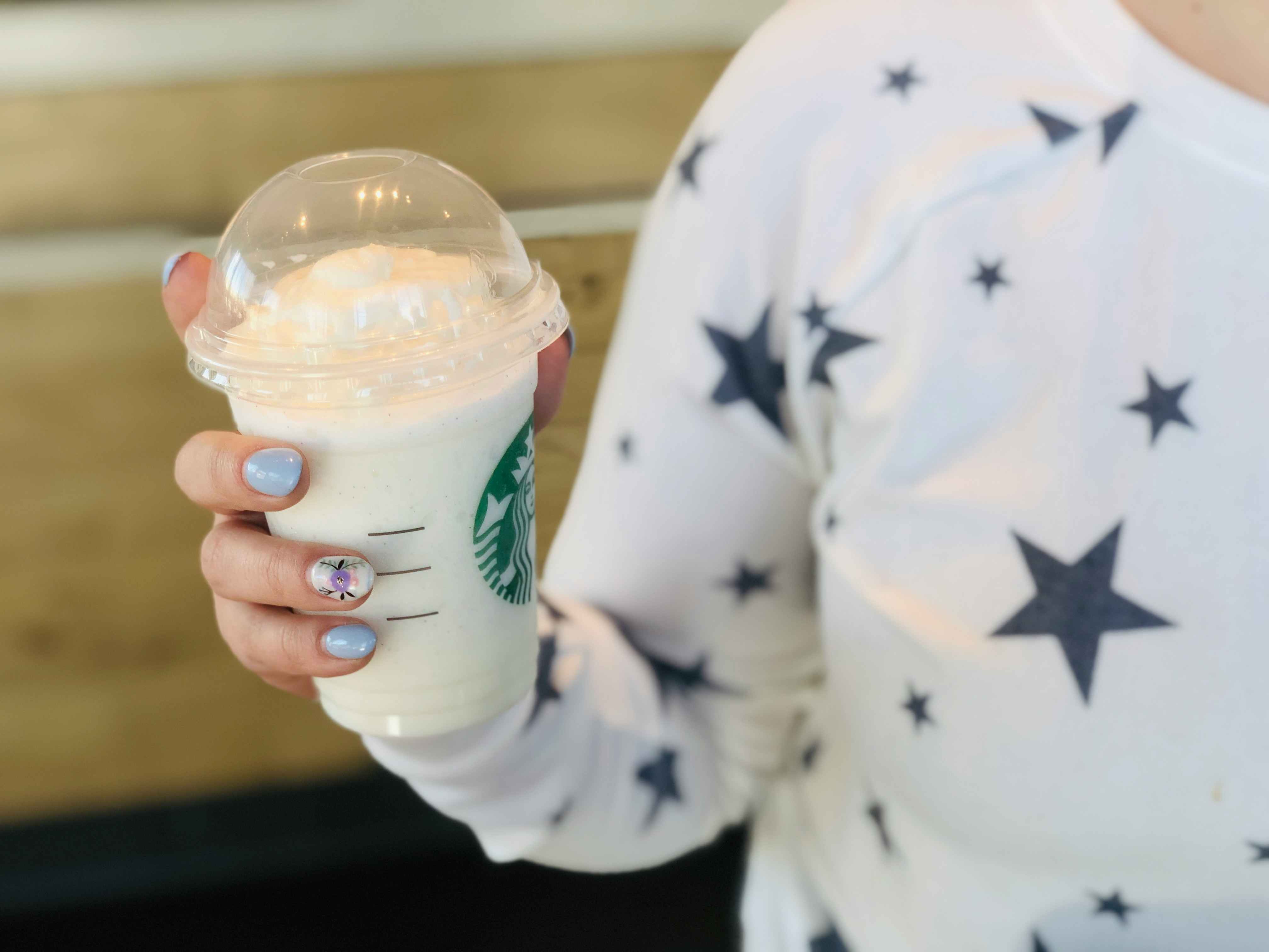 A person holding a frappuccino inside a Starbucks.