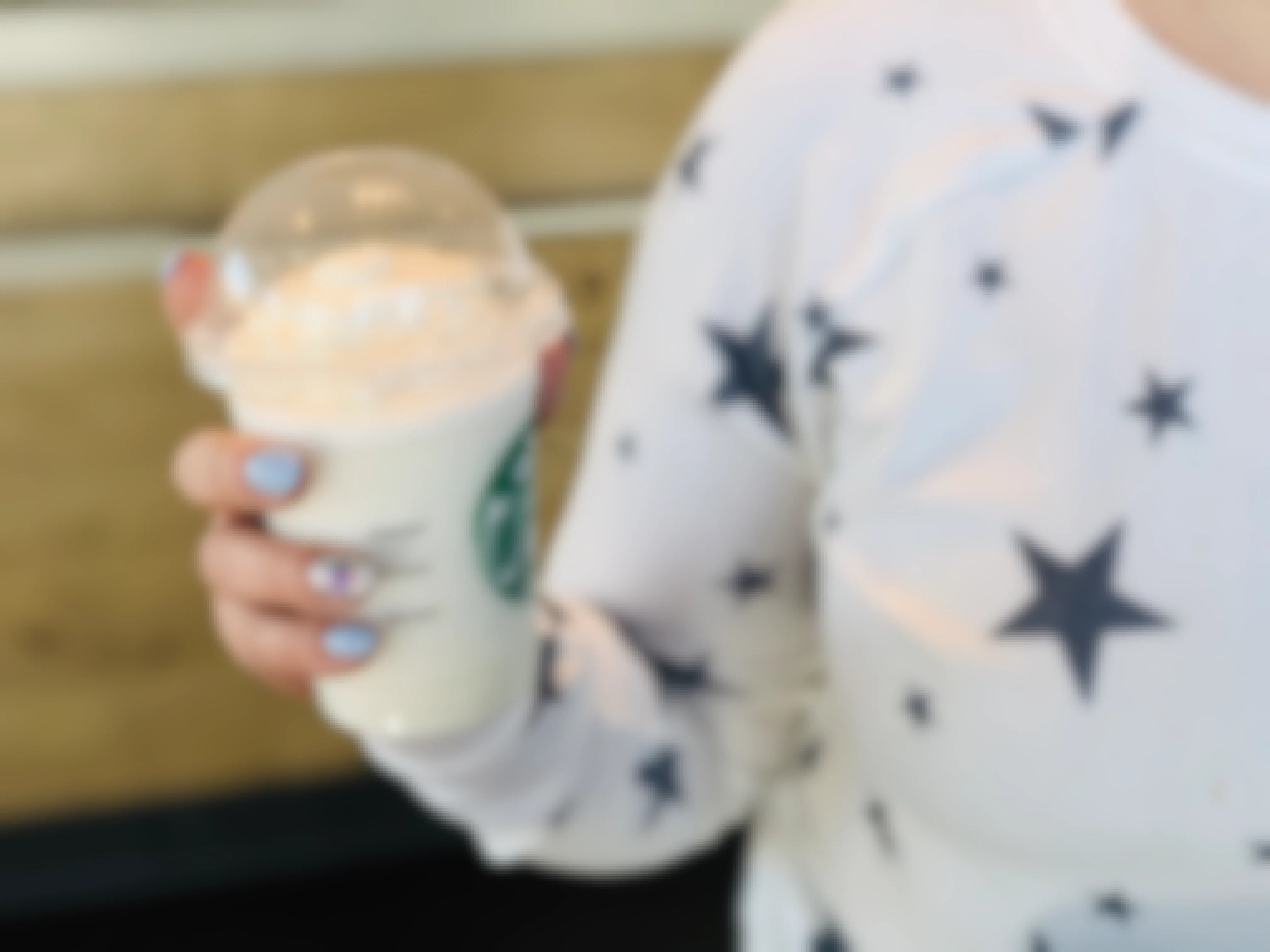 A person holding a frappuccino inside a Starbucks.