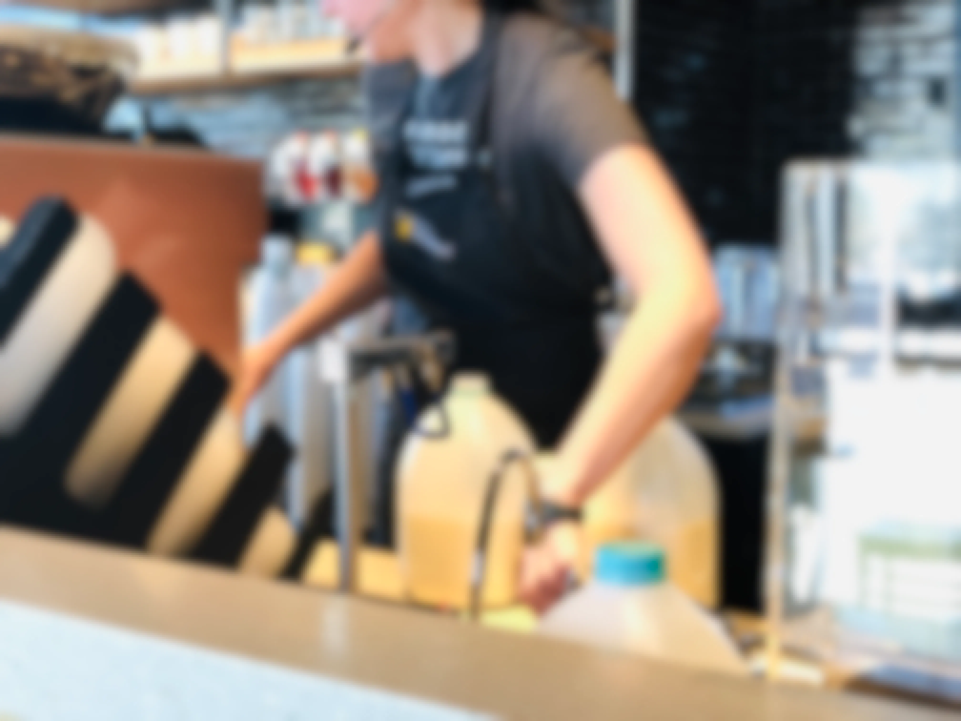 A Starbucks barista wearing a black apron working behind the counter at Starbucks. 