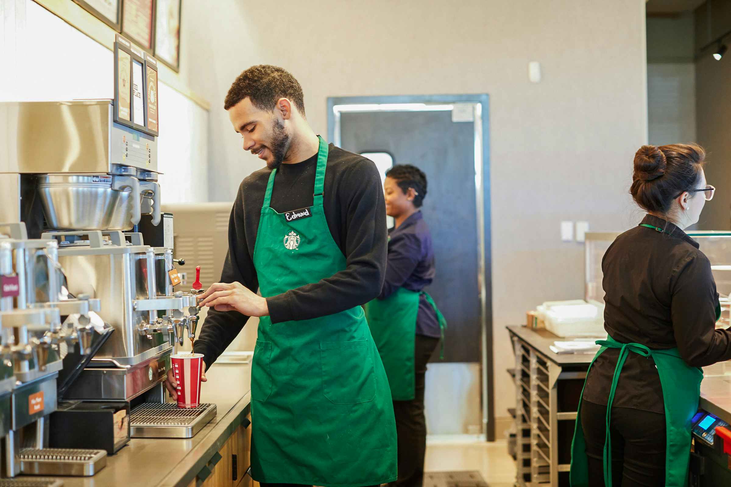 A barista making a drink behind the counter at Starbucks.
