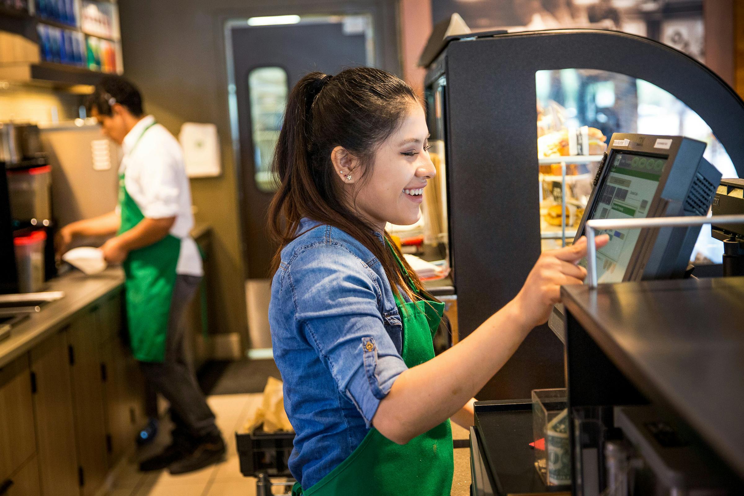 A barista entering a customer's order into a computer at Starbucks.