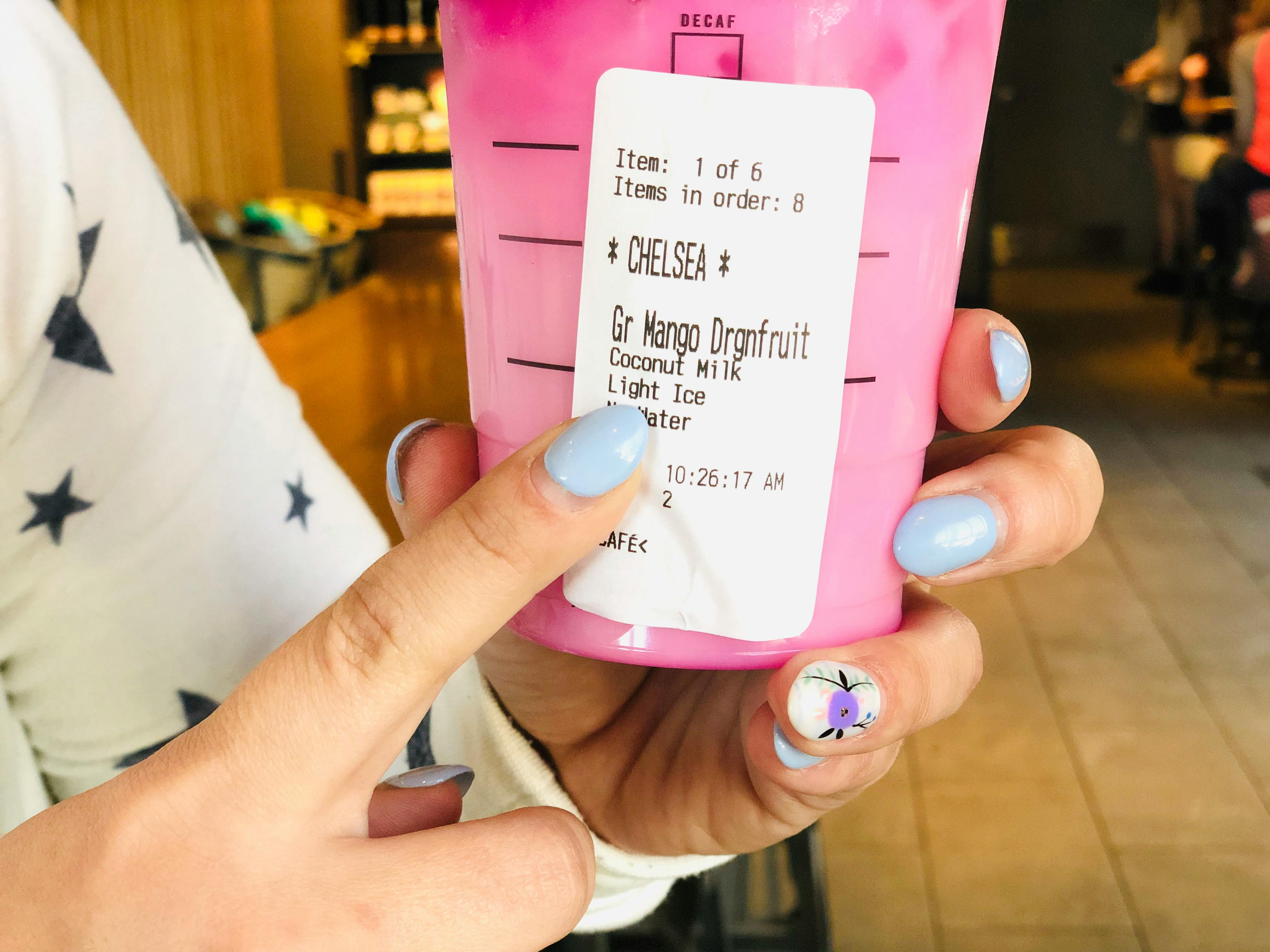 A person holding up a summer refresher drink from Starbucks and pointing to "Light Ice" printed on the label.