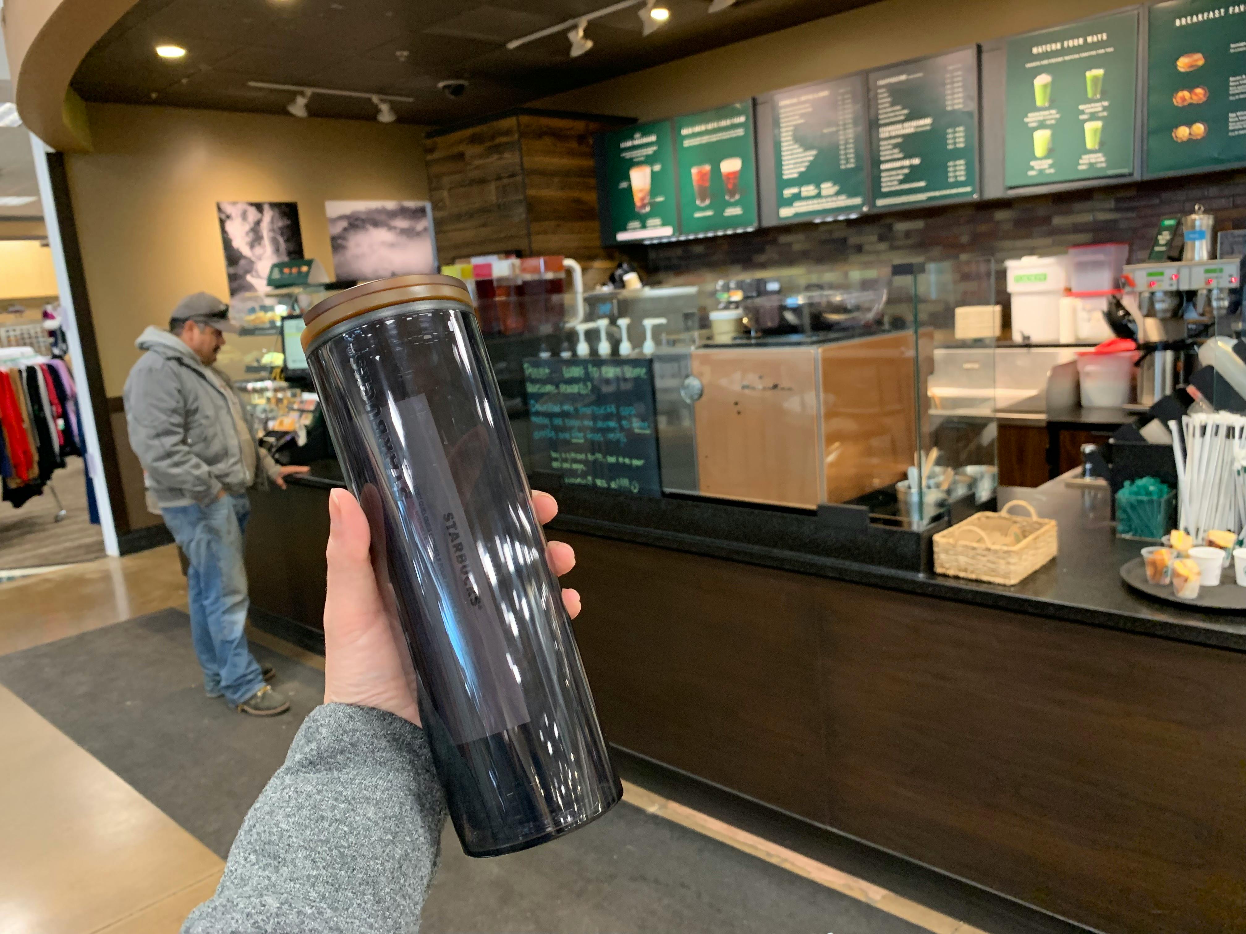 Starbucks customer holding reusable cup in front of ordering counter