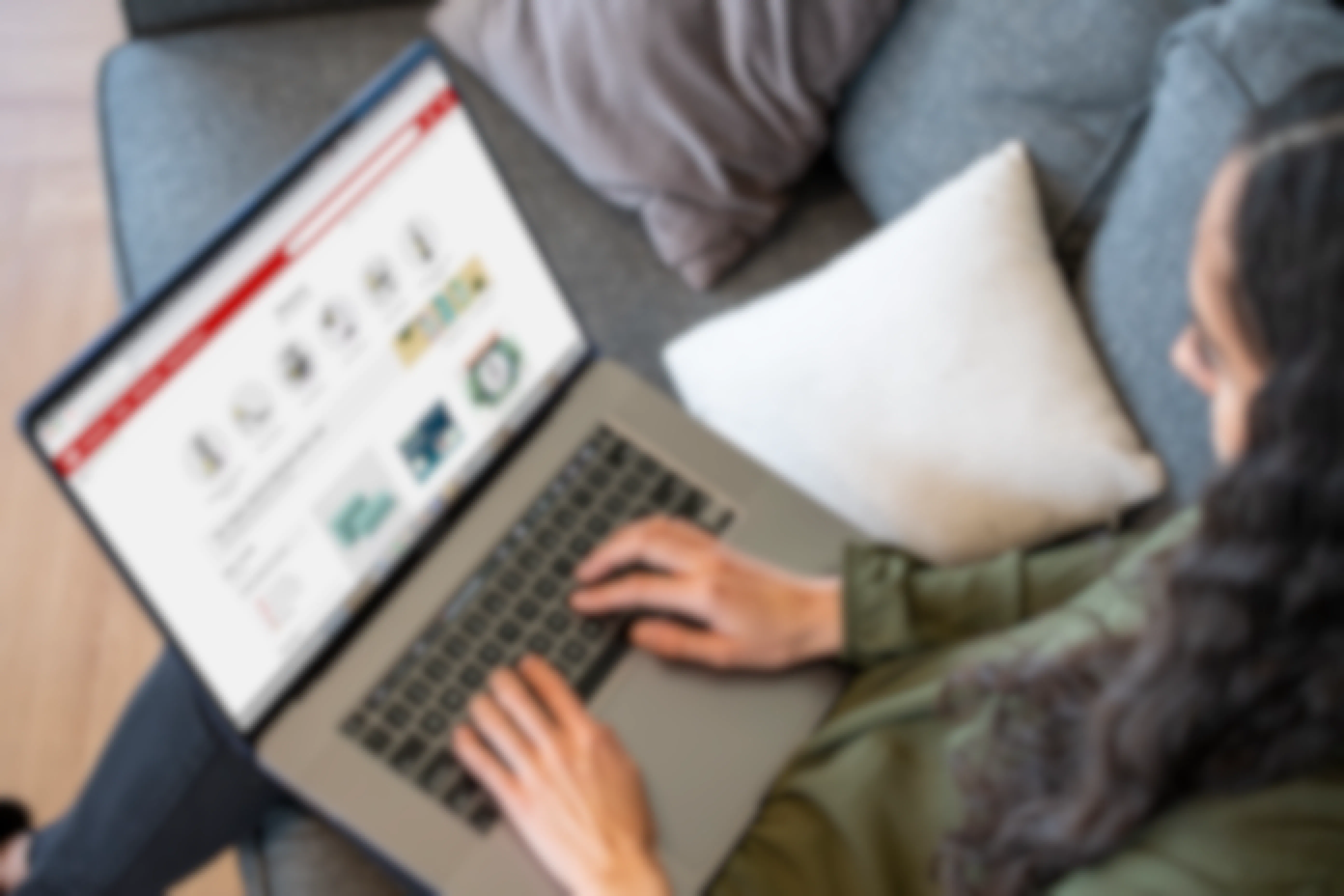 A Woman sitting on a sofa with a laptop on her lap displaying the target.com clearance page