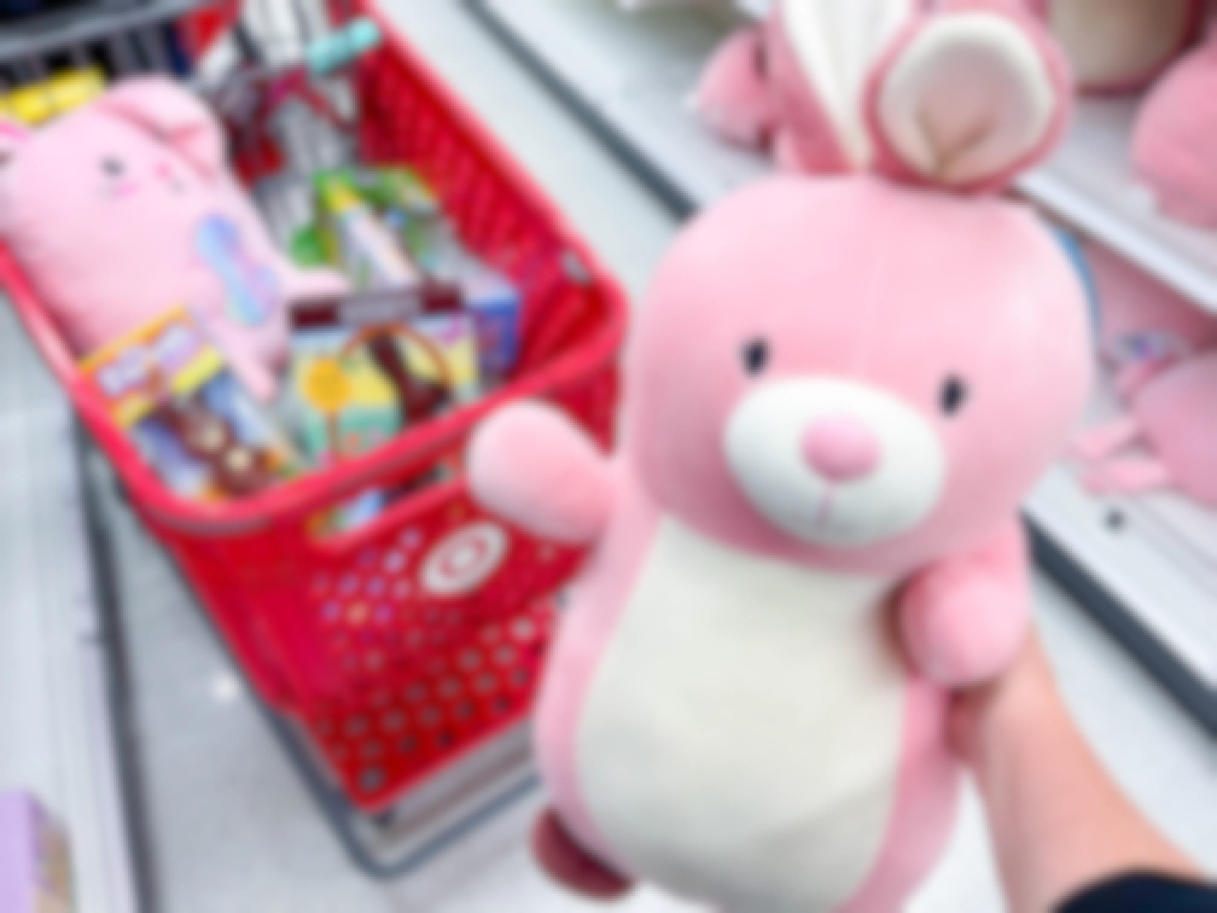 a large pink stuffed bunny being held in front of target cart filled with easter items