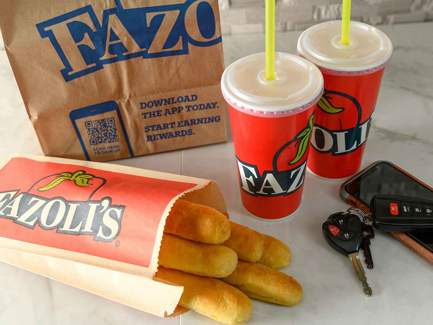 fazolis carry-out bag, breadsticks, drinks, phone, and keys on counter