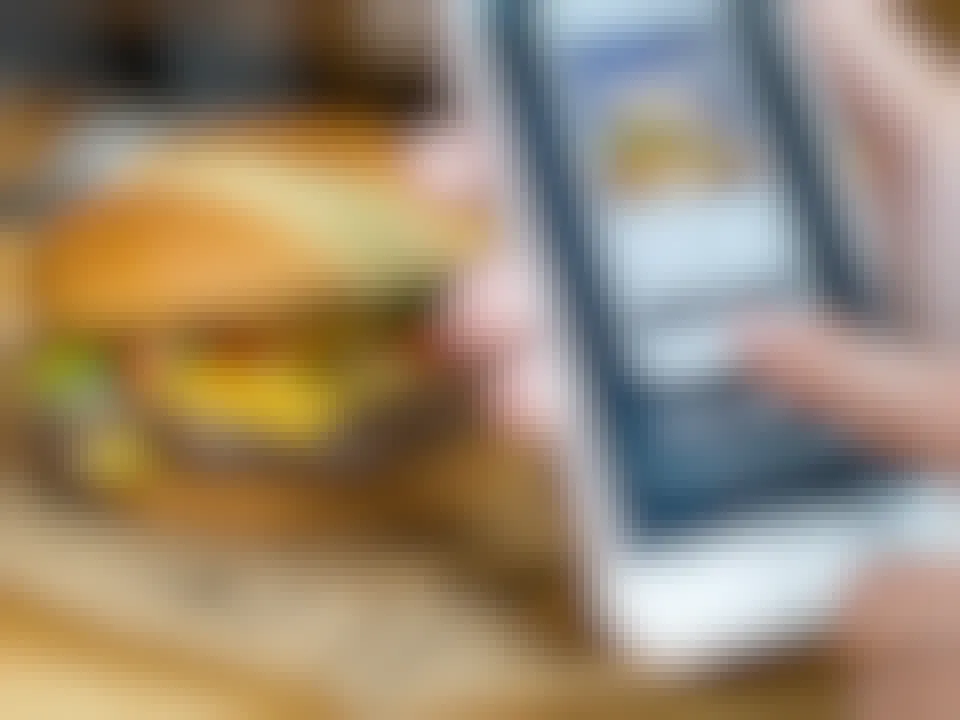 person on phone using wayback burgers app with food in the background