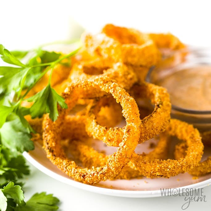Onion rings and a dipping sauce on a plate with parsley