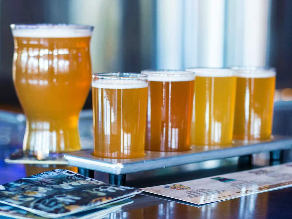 A large glass of beer next to four small ones on a table in a restaurant