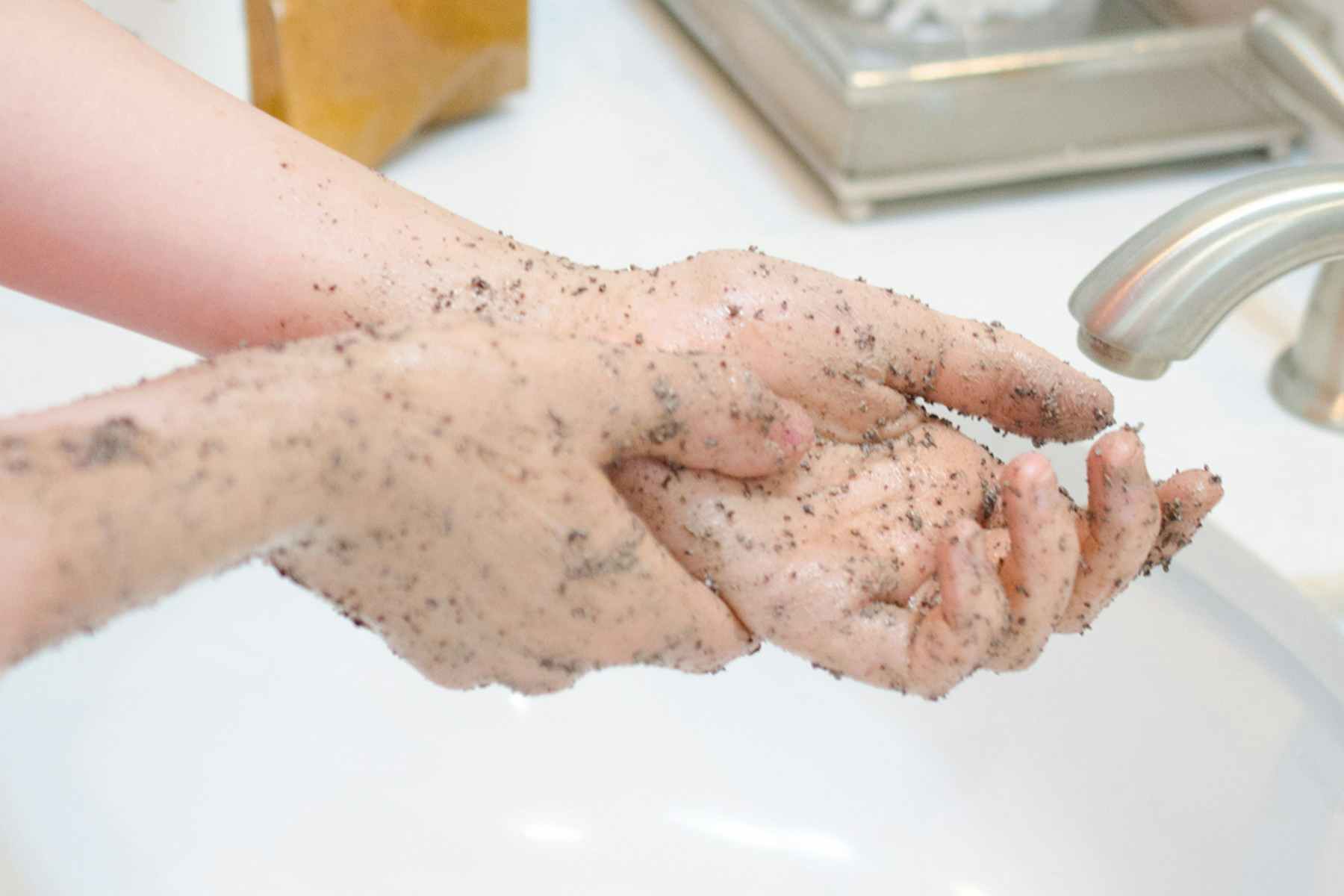 Person scrubbing hands and arms with a DIY body scrub.