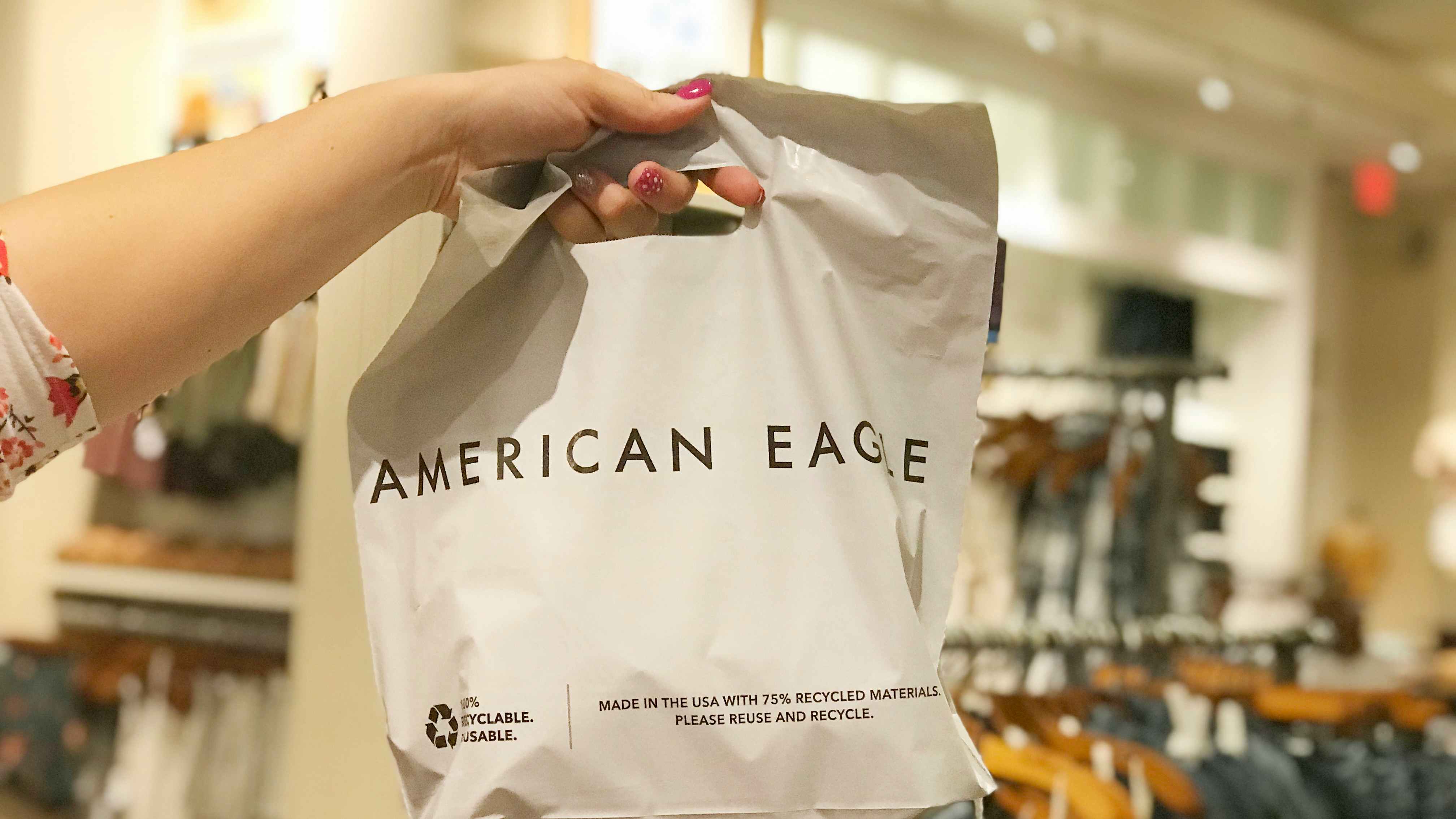 A person's hand holding up an American Eagle shopping bag.