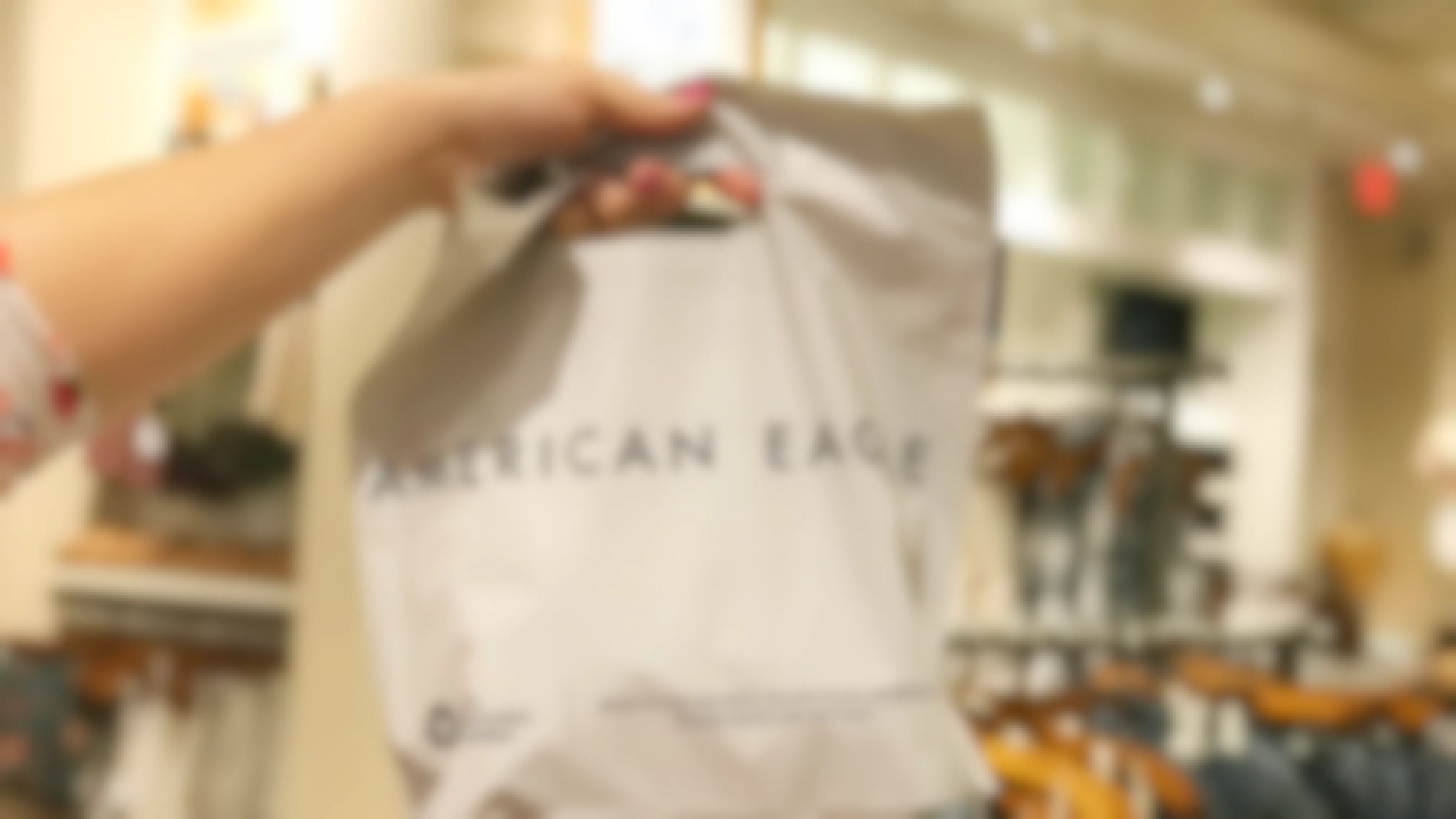 A person's hand holding up an American Eagle shopping bag.