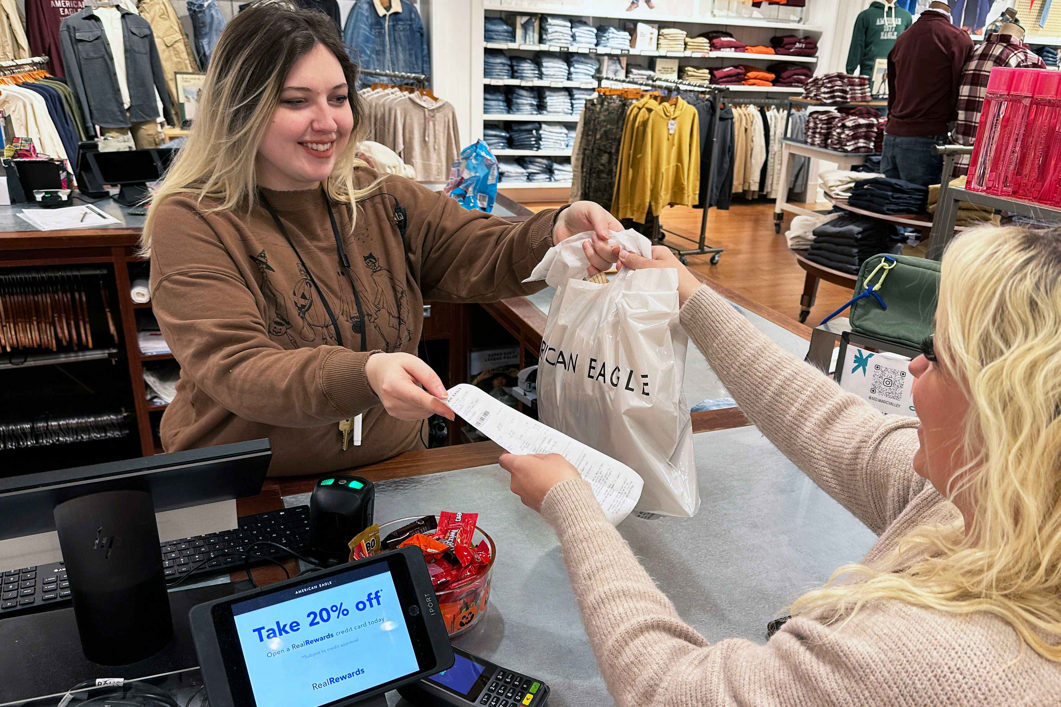 an american eagle employee giving a bag to a customer in store 