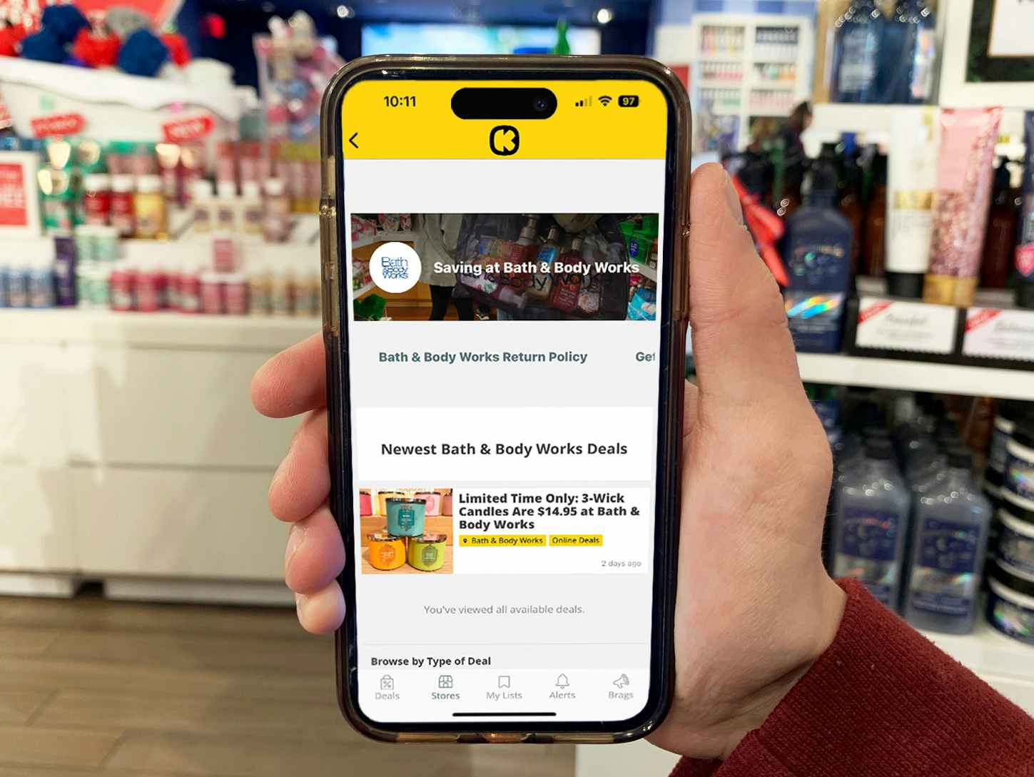 Someone holding a phone displaying The Krazy Coupon Lady app's page about Bath & Body Works sales.