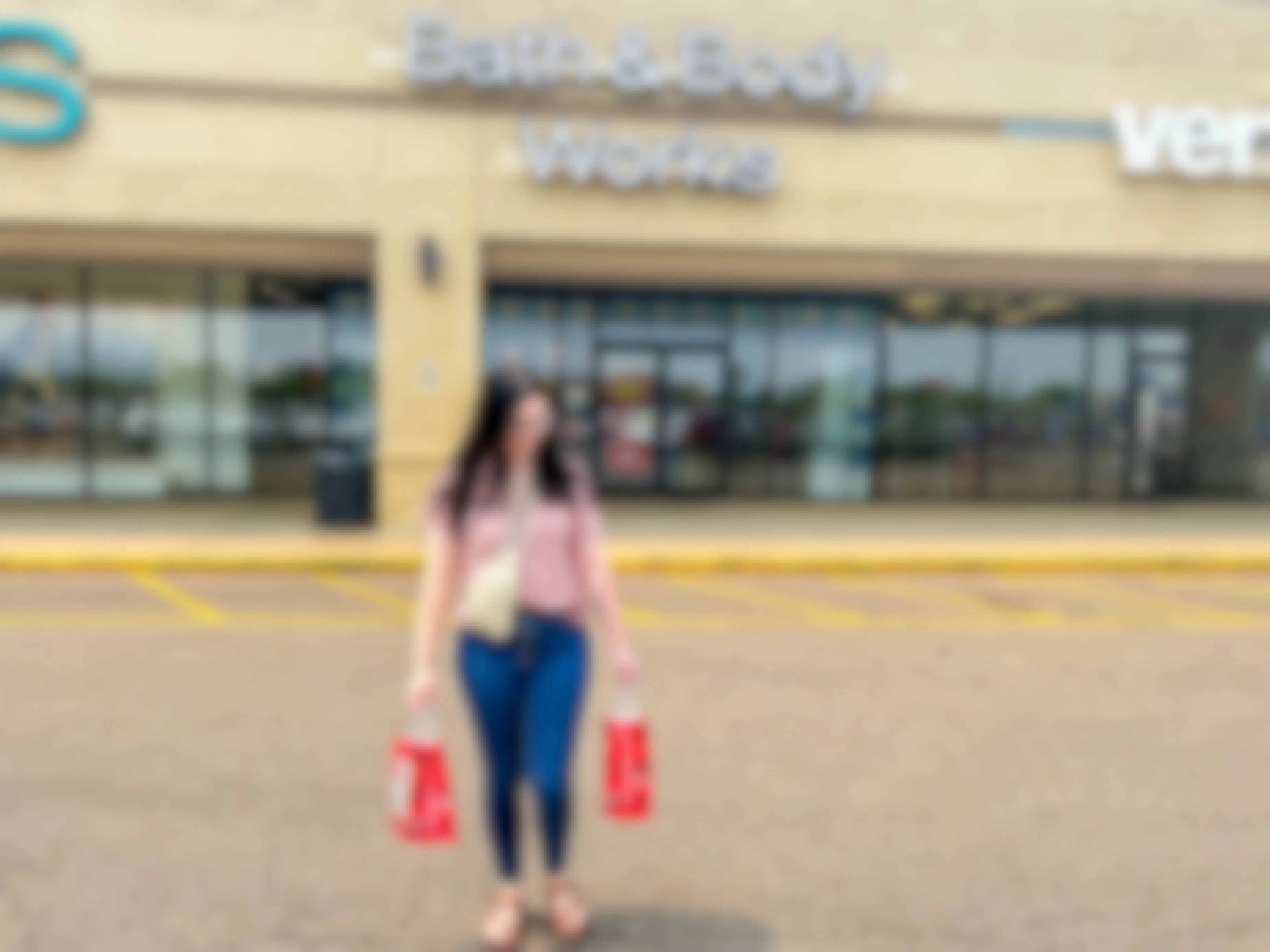 a person walking out of bath & body smiling while holding shopping bags