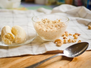 A bowl of oats made overnight next to a a halved banana and a spoon