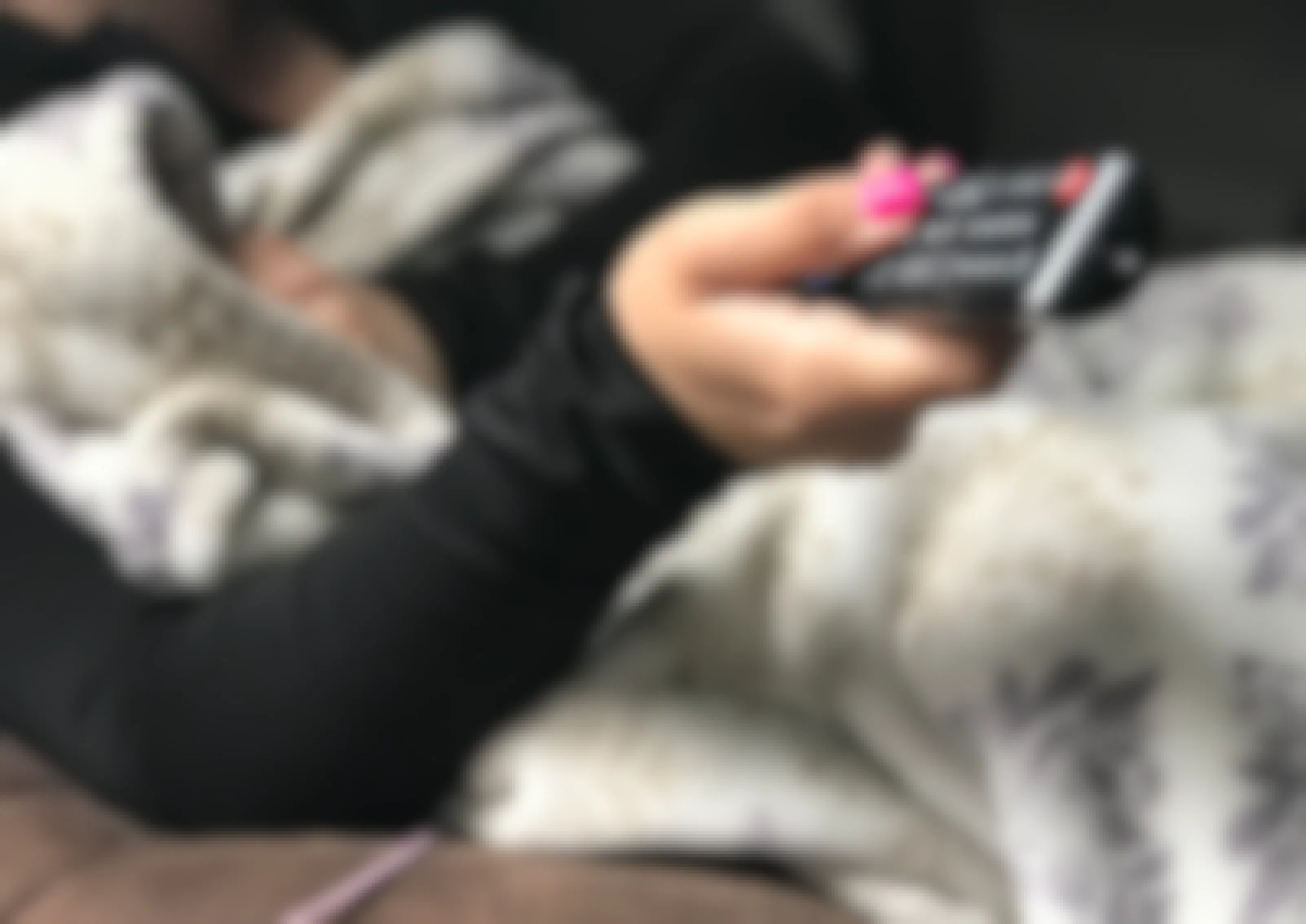 A person sitting on a couch with a blanket, holding a remote.