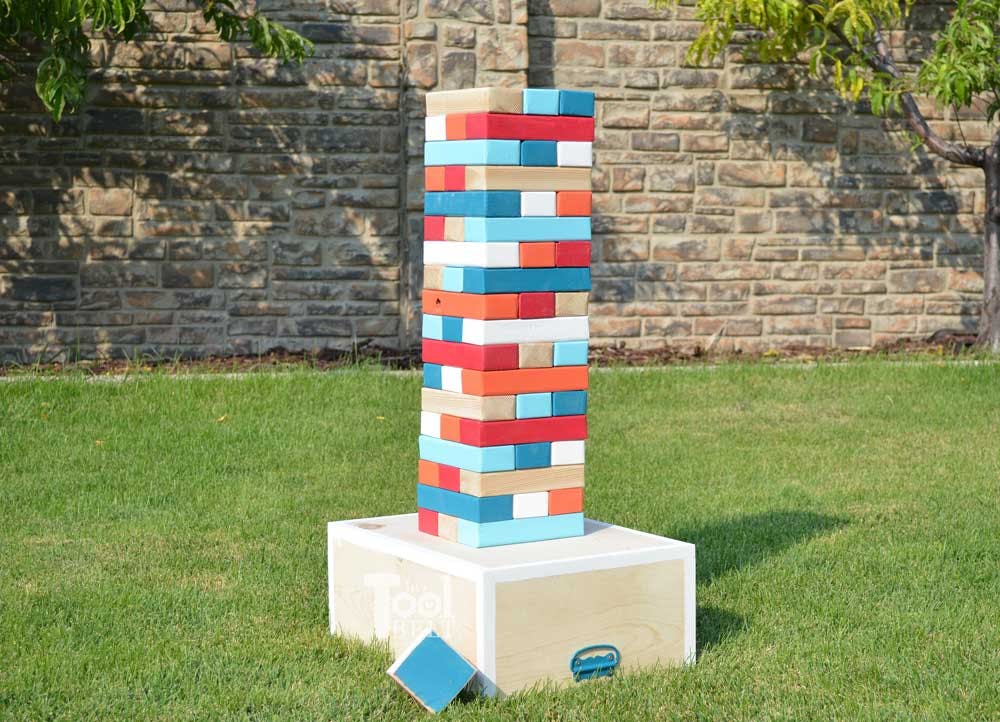 A giant DIY Jenga tower sitting on a box in a backyard.