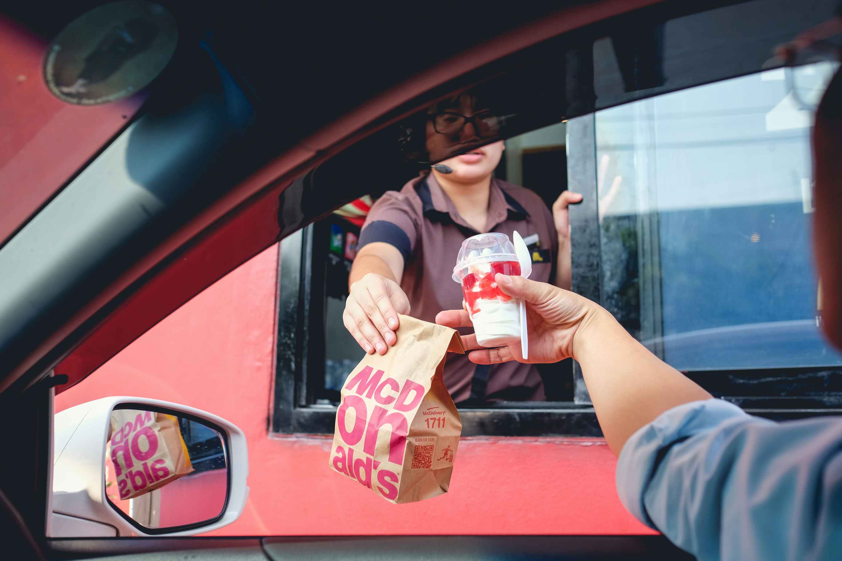 mcdonalds drive-thru employee handing food to driver through window