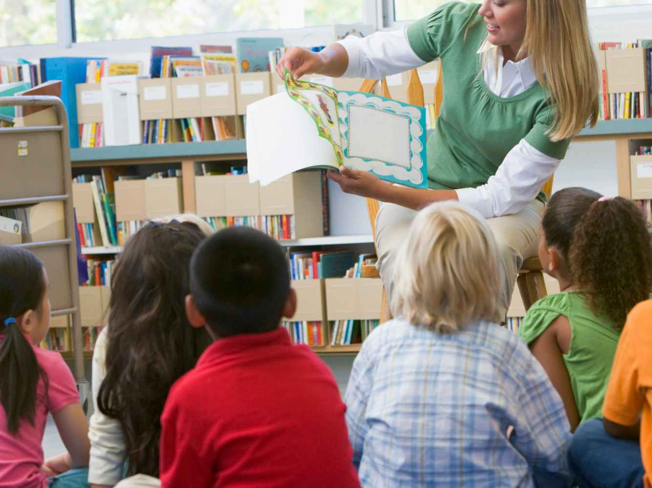 female teacher reading books kids library