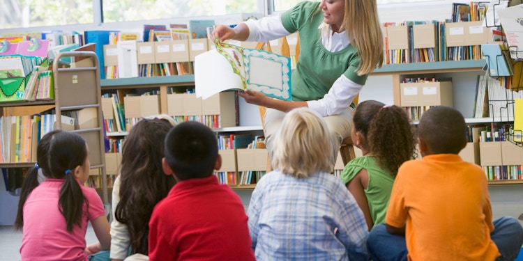 female teacher reading books kids library