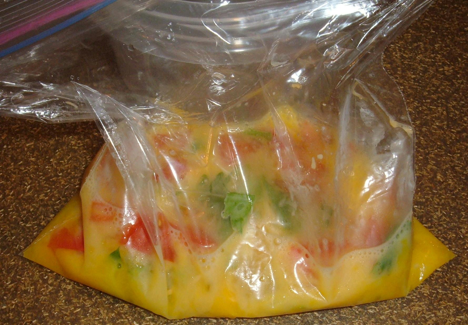A ziploc bag filled with raw scrambled eggs and omelet ingredients.