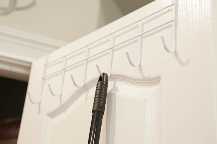 A broom hanging on a Dollar Tree Over-the-door hook