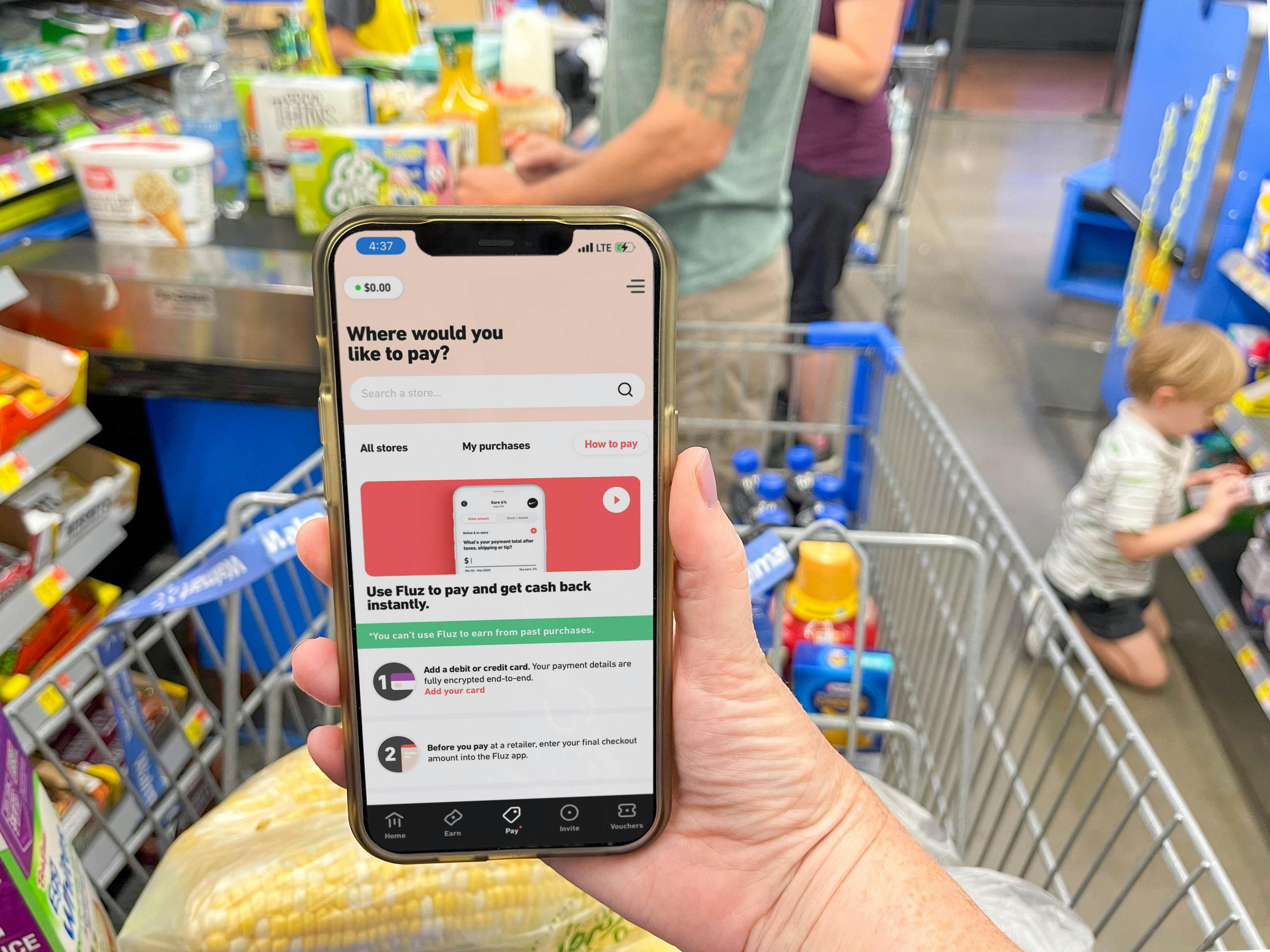 cellphone being held displaying the Fluz app in front of grocery store checkout