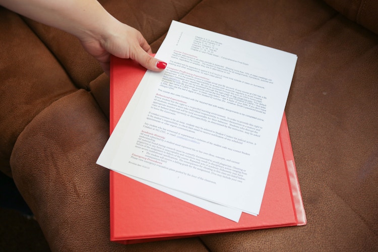 A person holding a printed recipe next to a Dollar Tree Three-ring binder