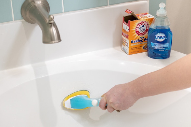 baking soda and Dawn dish soap sitting on the edge of a bathtub