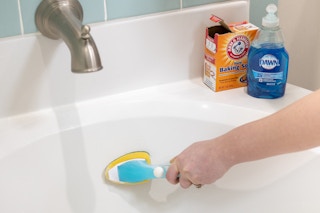 baking soda and Dawn dish soap sitting on the edge of a bathtub