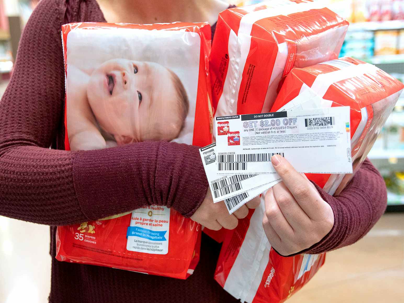 A person holding packages of baby diapers and coupons.