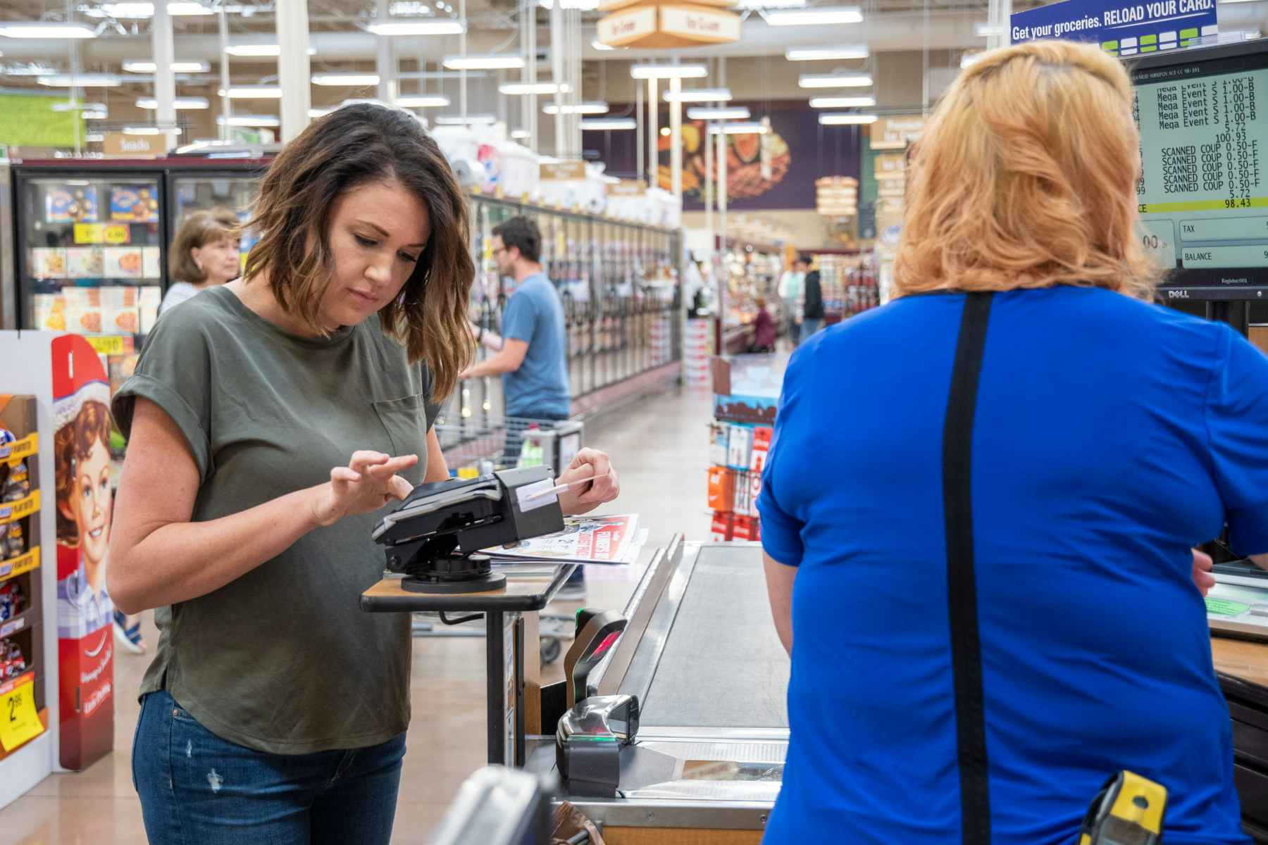 A woman typing in her phone number Alternate ID in a Kroger checkout lane.