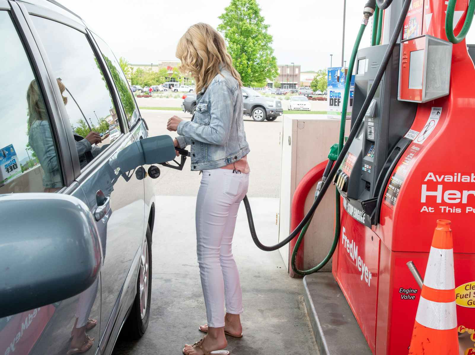 A woman filling her automobile with gas.
