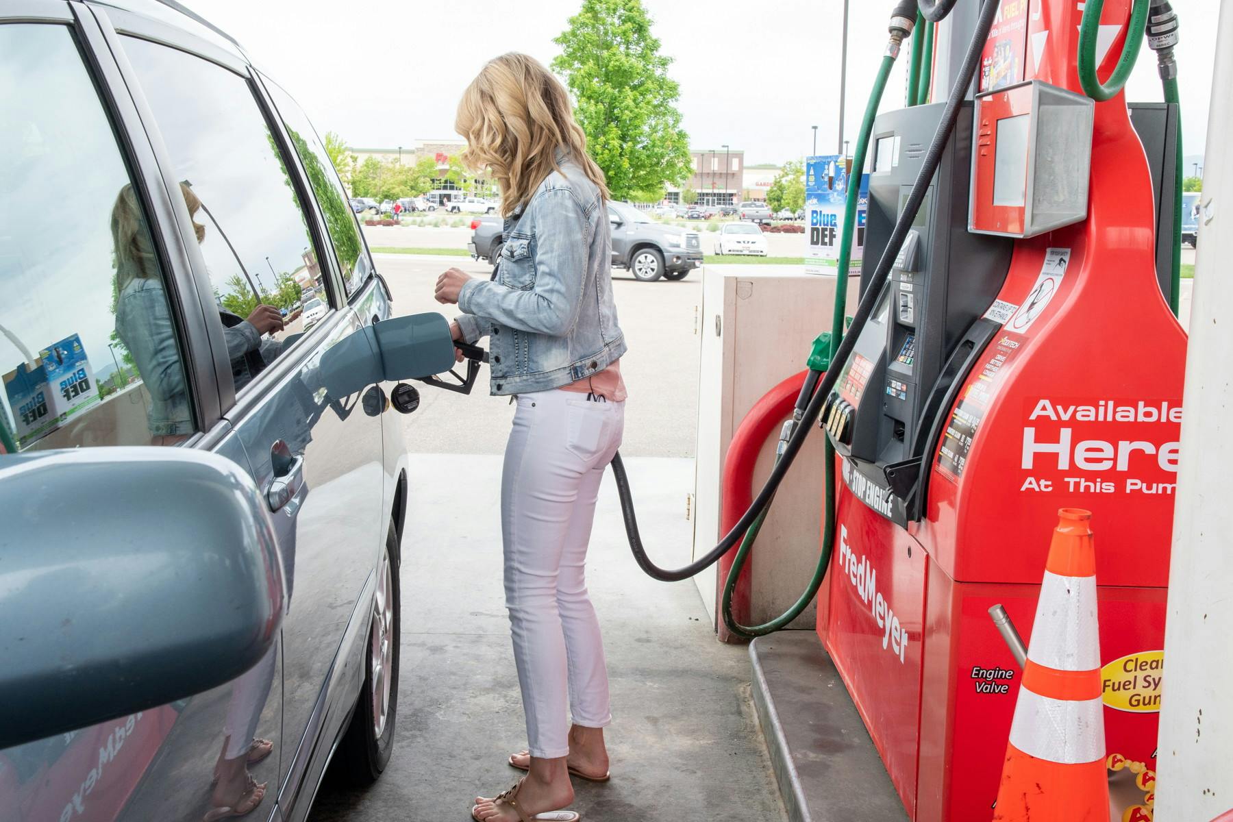 A woman filling her automobile with gas.