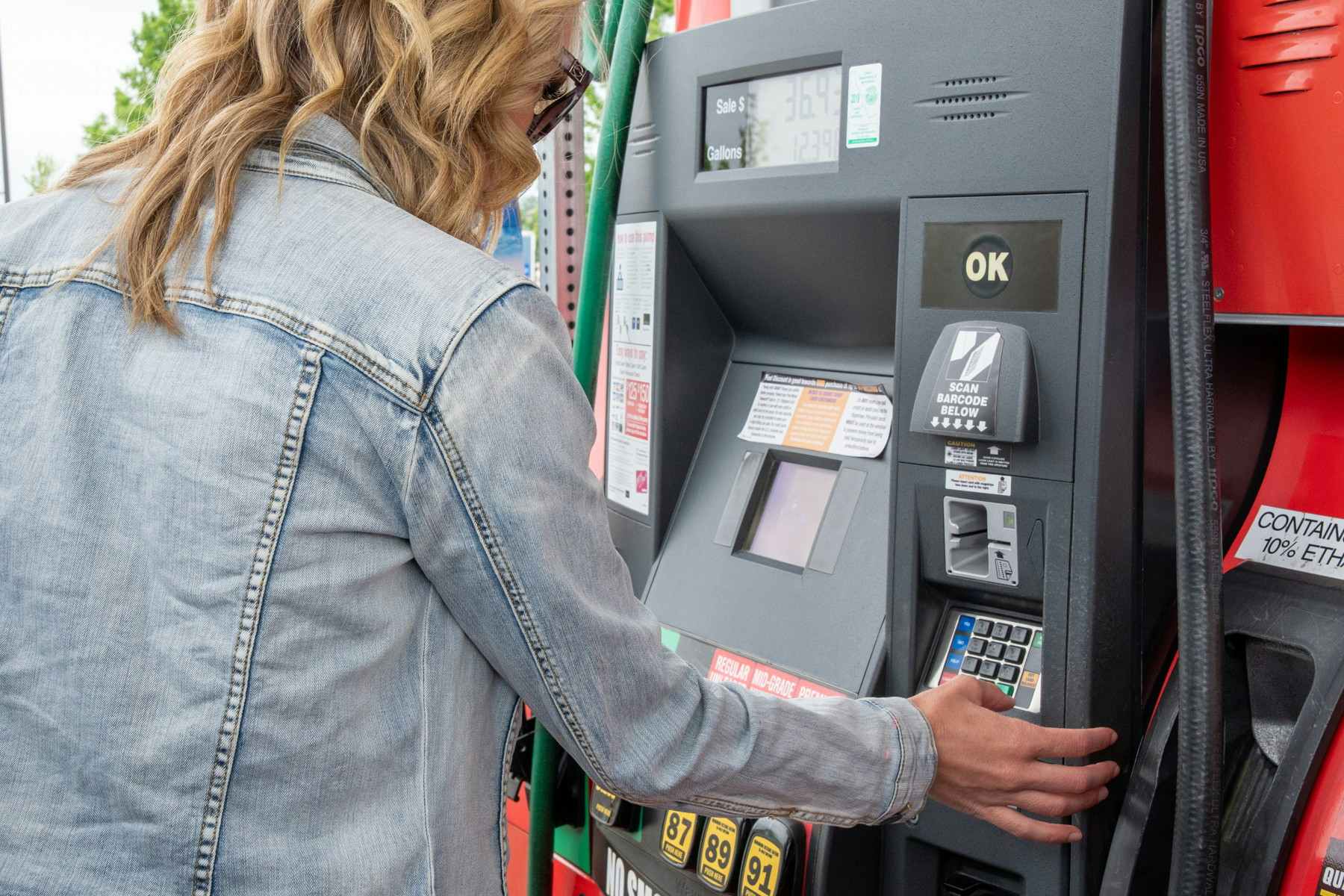 A woman putting in credit card info at the gas pump.