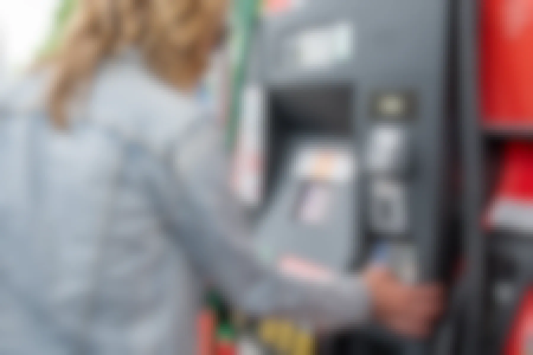 A woman putting in credit card info at the gas pump.