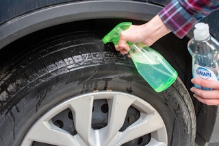 Person spraying a Dawn dish soap solution onto tires