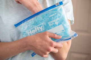 Person holding a hefty storage bag filled with Dawn Dish Soap on arm.