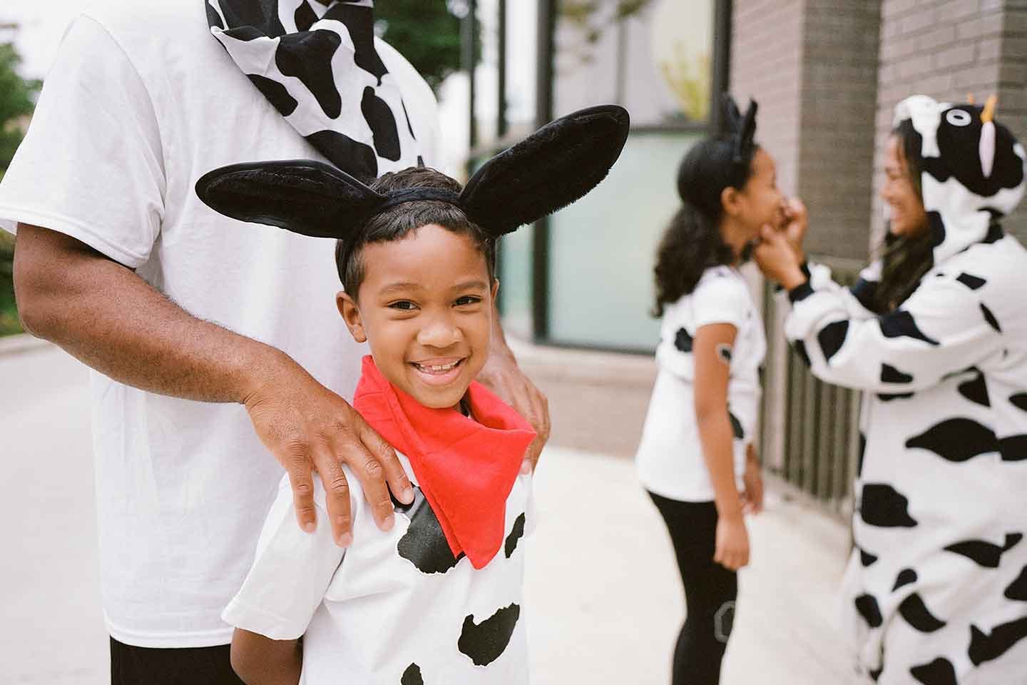 A child in a cow costume standing with cow-clad family for Chick-fil-A cow appreciation day.