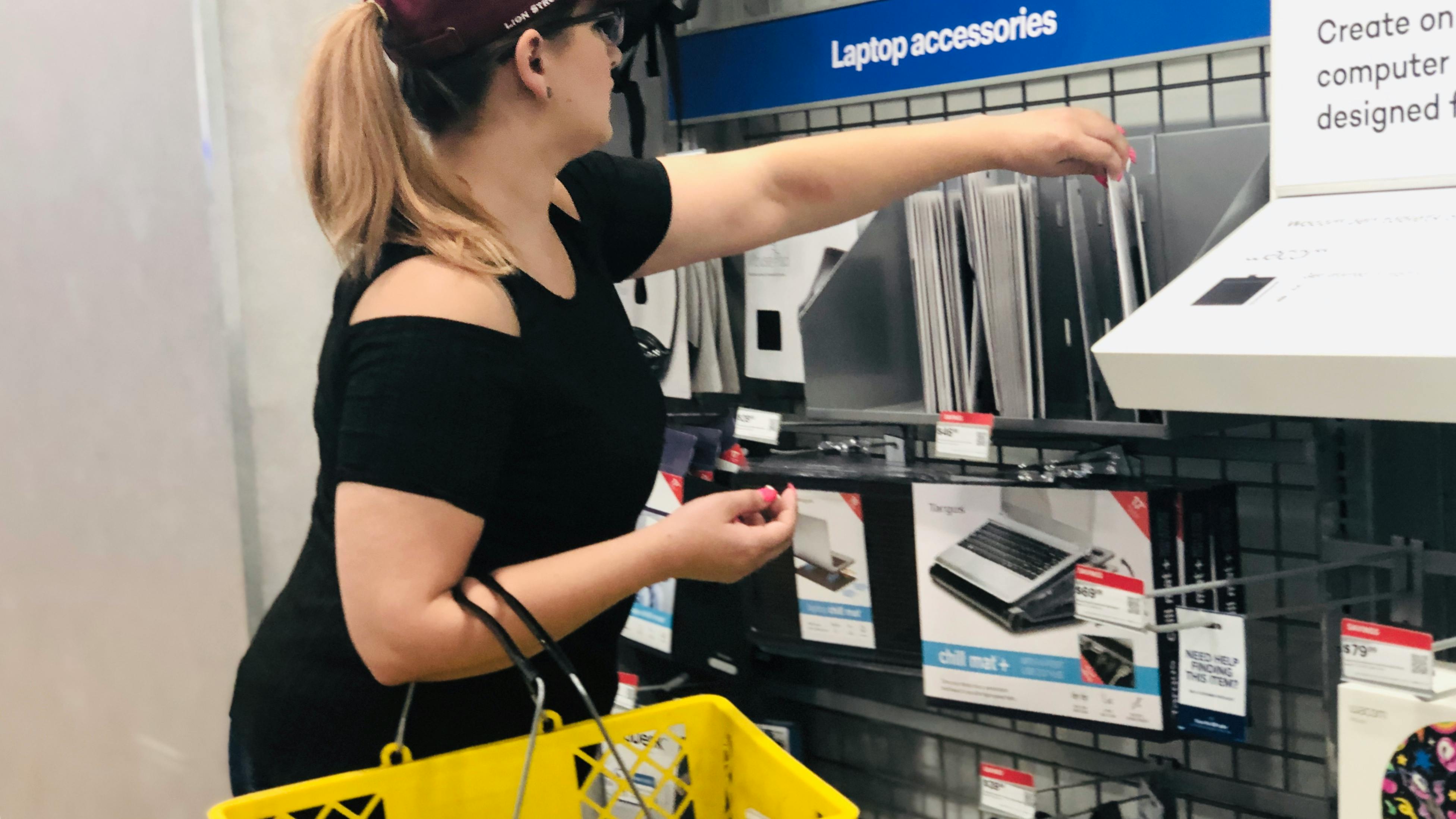 woman reaches for a laptop cord on best buy accessories wall